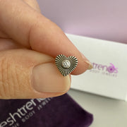 Diamond sunburst heart earring pinched between fingers with FreshTrends packaging behind