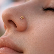 Dainty 14k gold flower nose ring shown in pierced nostril for scale and fit