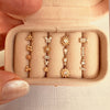 Close-up of travel jewelry box interior holding gold piercing studs, earrings, and CZ body jewelry