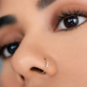 14k gold three-diamond side-set seam ring shown in a nostril piercing on model