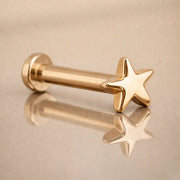 14k yellow gold star flat back labret stud angled on reflective surface showing post and disc backing