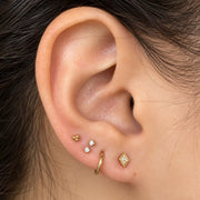 Curated gold ear stack with tiny charm flat back studs shown on a model's lobe and cartilage piercings