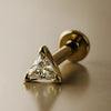 14k yellow gold 3mm triangle diamond flat back labret stud, angled lifestyle shot on warm background