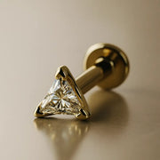 14k yellow gold 3mm triangle diamond flat back labret stud, angled lifestyle shot on warm background