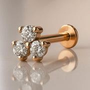 14k rose gold triple CZ flat back labret with three prong-set stones, angled view on reflective surface