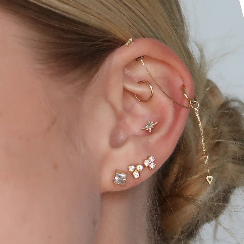 Close-up of triple CZ gold flat back stud in cartilage piercing within a styled gold ear stack