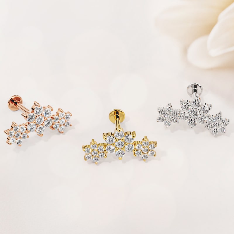 Triple flower flat back stud in rose gold, yellow gold, and white gold side by side near white flower