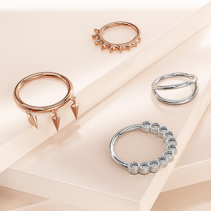 14k rose gold Hades seam ring styled alongside other 14k gold piercing rings on a neutral surface