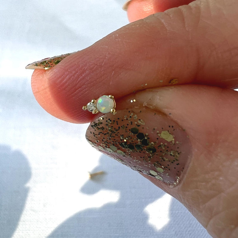 14k gold opal and diamond threadless stud end held between fingers for size reference