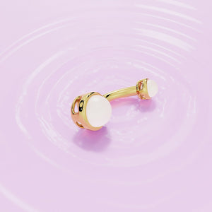 14k yellow gold dual Akoya pearl belly ring laid flat on rippled pink surface