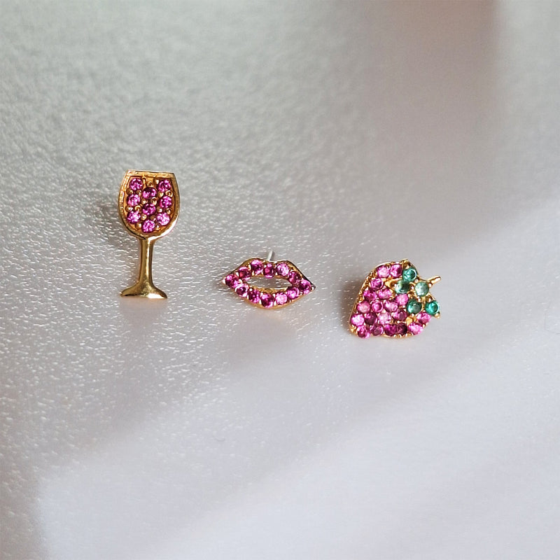 14K gold garnet lips flat back earring styled with wine glass and strawberry earrings on soft surface