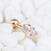 14k rose gold pear shaped diamond cartilage earring resting on white pebbles, side profile view