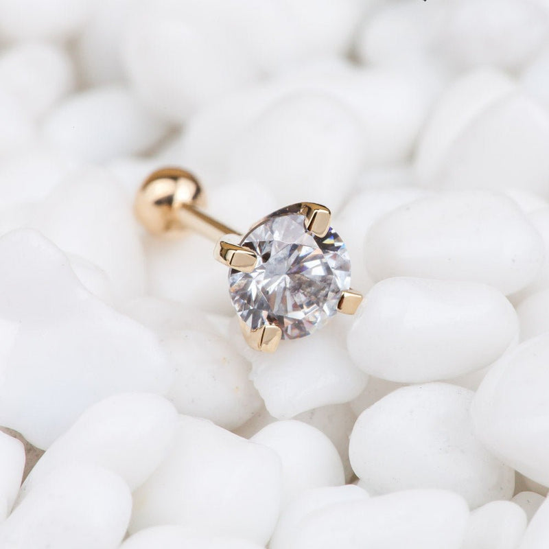 5mm diamond prong-set 14k yellow gold cartilage stud resting on white pebbles, lifestyle shot