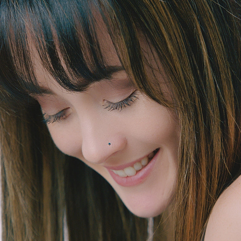 1.5mm blue diamond nose stud shown in pierced nose on smiling model, subtle everyday look