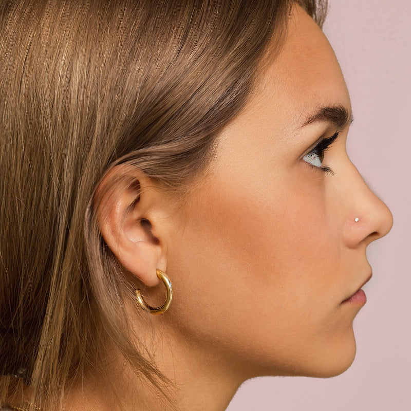 Dainty 14k gold CZ nose stud shown on model's pierced nose, side profile view
