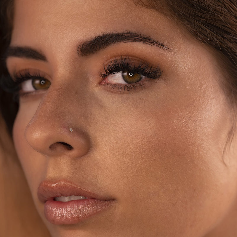 14k gold 1.7mm diamond nose stud shown on model with olive skin, angled three-quarter view