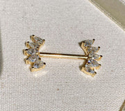 14k yellow gold white sapphire crescent nipple barbell resting on linen fabric, lifestyle shot