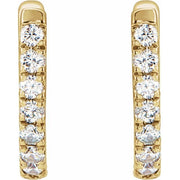Close-up front view of 14k yellow gold huggie hoops highlighting pave diamond row setting