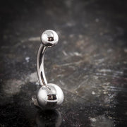 14k white gold double ball navel ring standing upright on dark reflective surface, front view