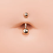 14k rose gold double ball navel ring shown close-up in belly piercing on silicone model