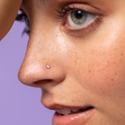 2mm diamond prong nose stud worn in pierced nostril, close-up fit view on model with freckles