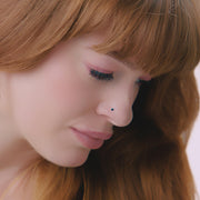 2mm blue diamond prong nose stud shown in pierced nose on model, demonstrating dainty fit