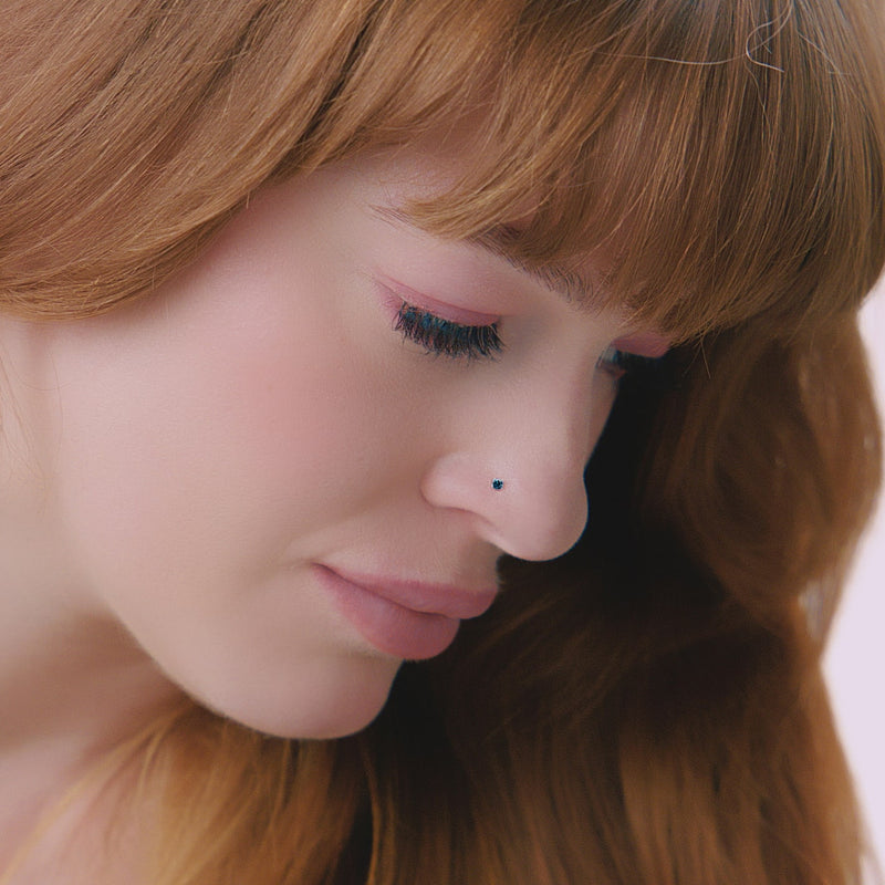 2mm blue diamond prong nose stud shown in pierced nose on model, demonstrating dainty fit