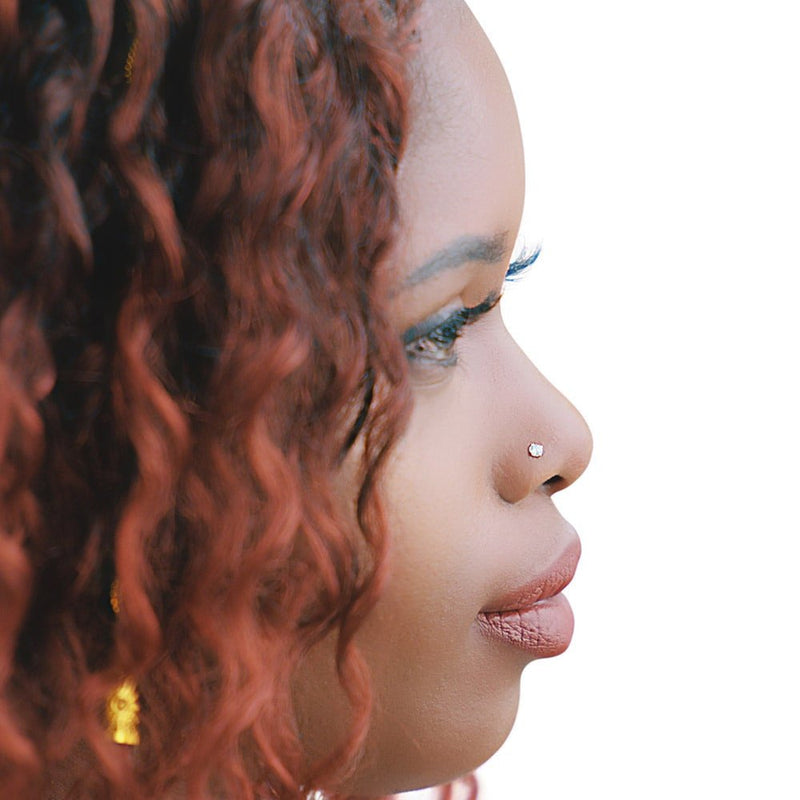 14k gold CZ nose ring worn in piercing on model with curly hair, side profile lifestyle shot