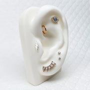 14k gold CZ flat back stud shown on white ear display with mixed piercing jewelry styling