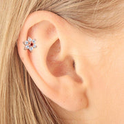 14k rose gold CZ flower stud with red center stone worn in helix piercing, close-up on model