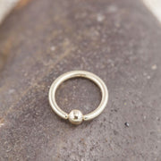 14K white gold fixed bead ring resting on smooth stone, angled lifestyle shot