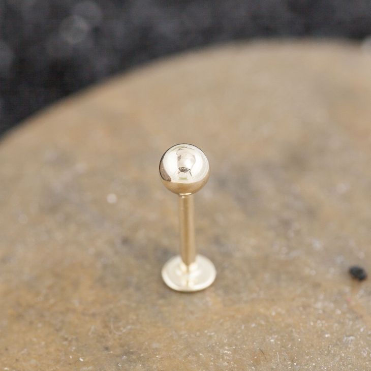 Close-up of 14K gold 5mm ball flat back labret stud showing polished ball and flat disc backing