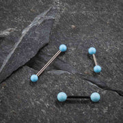 Multiple simulated turquoise straight barbells in varied metal tones displayed on dark slate stone surface