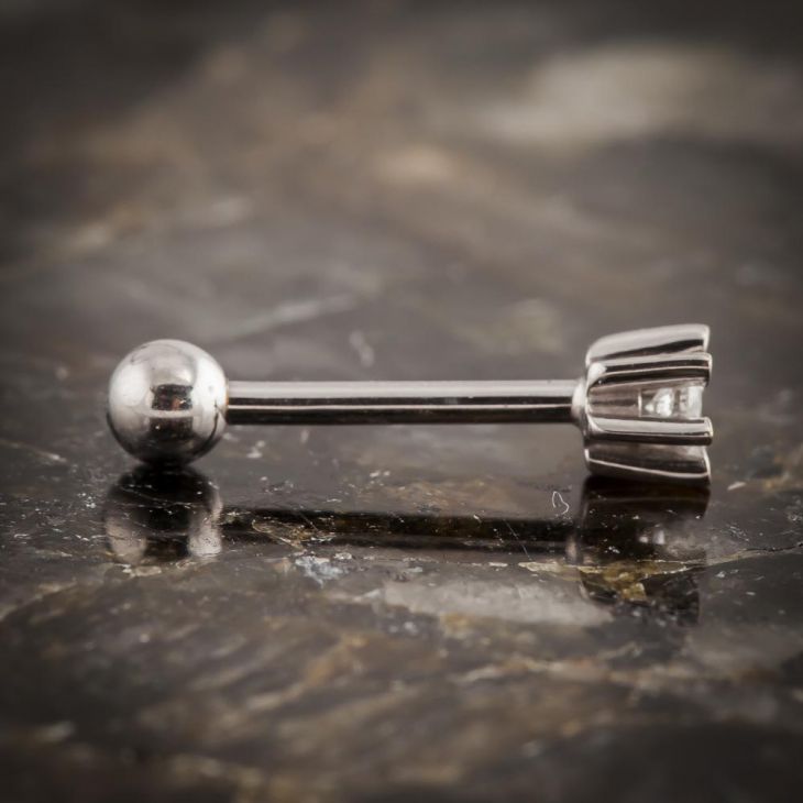 Side profile of 14k white gold diamond flower helix stud on stone surface highlighting barbell and petal base
