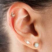 14K gold spider labret worn in a tragus piercing, styled with gold ear stack for scale
