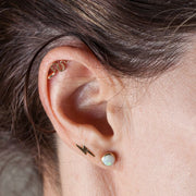 Gold snake cartilage stud shown in helix piercing, styled with lightning bolt and opal lobe studs