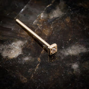 14K yellow gold square CZ nose stud with straight post, angled on dark stone surface