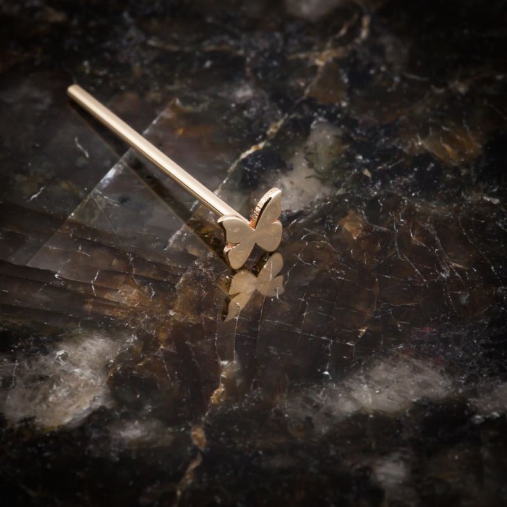 14K rose gold butterfly nose ring straight post style on dark marble surface