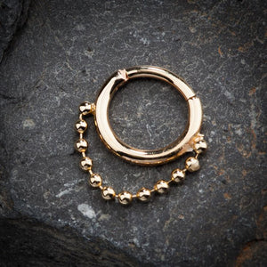 14K gold beaded chain clicker ring styled on dark stone surface, lifestyle shot