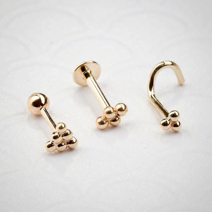 14K rose gold trinity bead design shown in barbell, labret, and nose screw styles