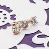 14K rose gold trinity heart CZ belly ring laid flat on decorative surface, overhead lifestyle view