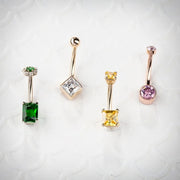 Green CZ flower cluster navel ring alongside three other 14k gold belly ring styles for comparison
