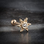 14K yellow gold sunburst helix stud with CZ, styled on dark stone surface showing handcrafted detail