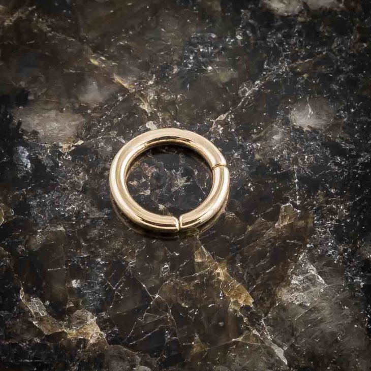 14K yellow gold segment ring closed, flat lay on dark marble showing polished finish