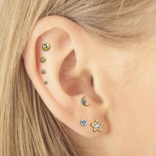 Yellow gold crescent moon opal labret shown in helix piercing, styled in curated ear stack on model