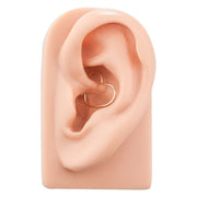 14K gold heart seam ring worn in daith piercing on silicone ear model, angled side view