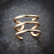 14k yellow gold three-band ear cuff on dark stone surface showing spiral wrap detail