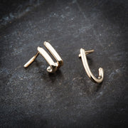 Two 14K yellow gold faux hoop nose rings on dark stone surface showing front and side angles
