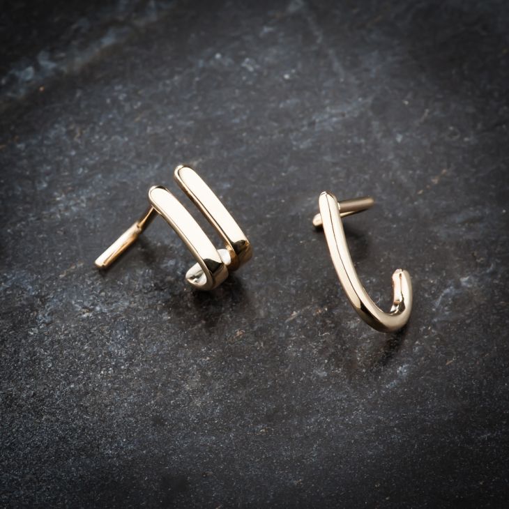 Two 14K yellow gold faux hoop nose rings on dark stone surface showing front and side angles