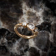 14k yellow gold three-CZ engagement-style clicker ring resting on dark marble surface
